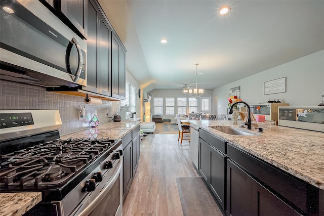 kitchen featuring light wood finished floors, tasteful backsplash, open floor plan, stainless steel appliances, and a sink