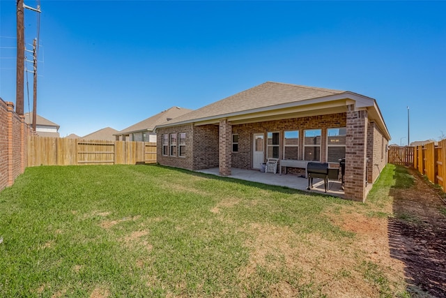 back of house with brick siding, a shingled roof, a lawn, a patio area, and a fenced backyard