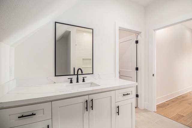 bathroom featuring lofted ceiling, a textured ceiling, wood finished floors, and vanity