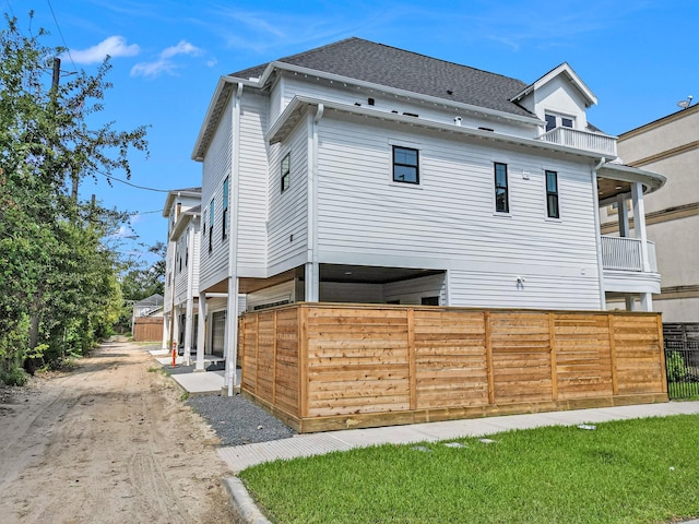 view of side of home with a shingled roof and fence