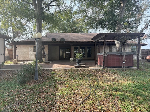 back of house with a patio, brick siding, and a hot tub