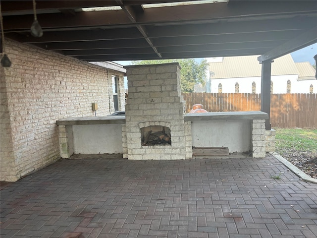 view of patio featuring fence and exterior fireplace