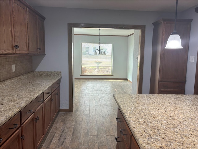 kitchen with hanging light fixtures, baseboards, decorative backsplash, and wood finished floors