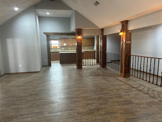 unfurnished room with dark wood-style floors, baseboards, visible vents, and high vaulted ceiling