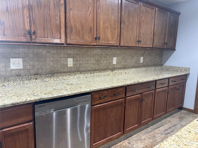 kitchen with baseboards, decorative backsplash, light stone countertops, light wood-type flooring, and stainless steel dishwasher