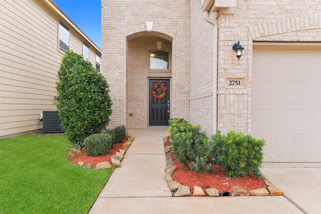 property entrance with a garage, brick siding, and cooling unit