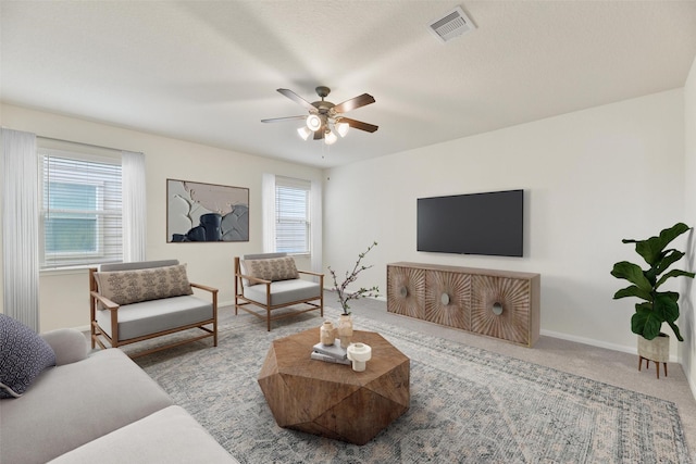 living area with a ceiling fan, carpet, visible vents, and plenty of natural light