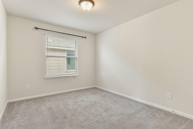 carpeted spare room featuring baseboards