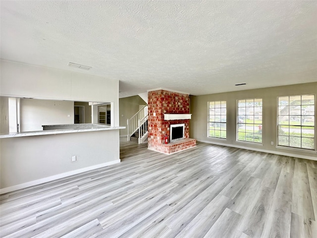 unfurnished living room featuring plenty of natural light, a fireplace, visible vents, and wood finished floors