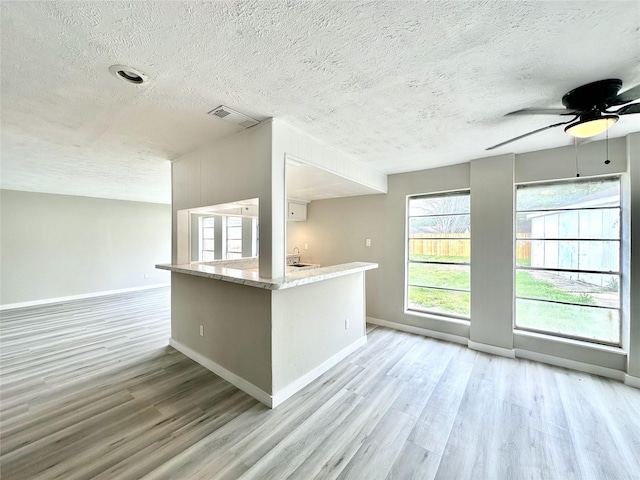 unfurnished room featuring ceiling fan, light wood finished floors, visible vents, and baseboards