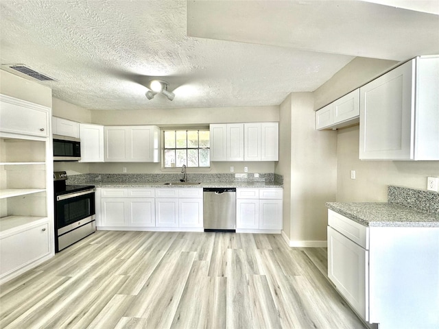 kitchen with light wood finished floors, visible vents, white cabinets, stainless steel appliances, and a sink