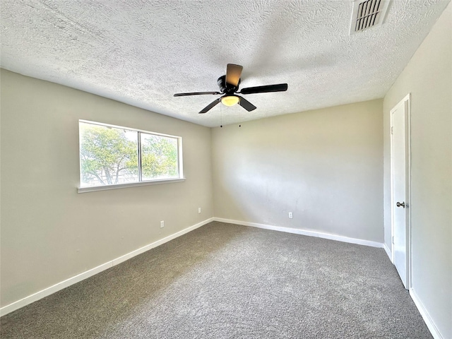 spare room with dark colored carpet, visible vents, ceiling fan, and baseboards