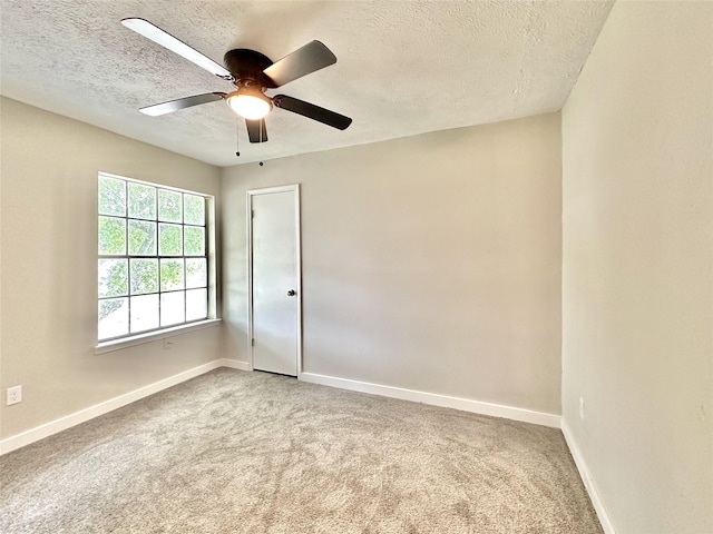 empty room with a textured ceiling, carpet flooring, and baseboards