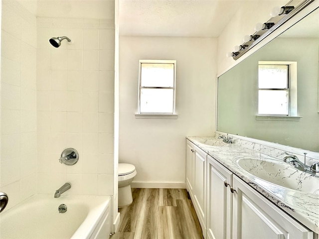 bathroom featuring double vanity, a sink, toilet, and wood finished floors