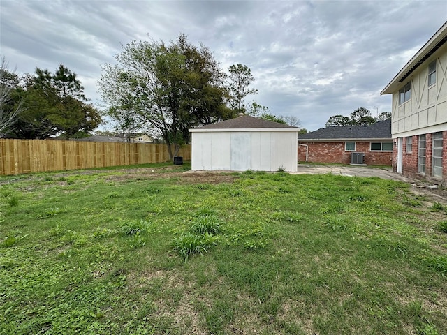 view of yard featuring a patio, cooling unit, an outdoor structure, fence, and a storage unit