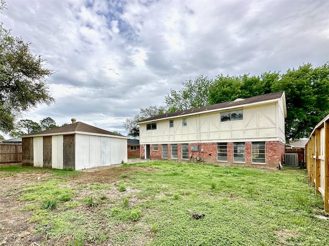 back of house with brick siding, fence, a lawn, and central AC unit