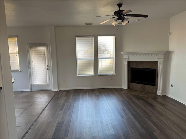 unfurnished living room with a ceiling fan, dark wood-style floors, visible vents, and a tile fireplace