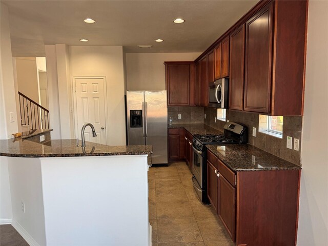 kitchen with dark stone countertops, a sink, tasteful backsplash, recessed lighting, and appliances with stainless steel finishes