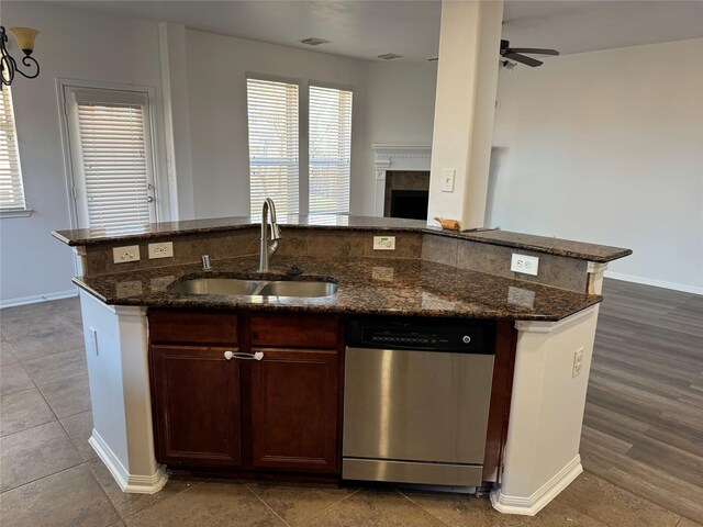 kitchen with a kitchen island with sink, a sink, open floor plan, a fireplace, and dishwasher