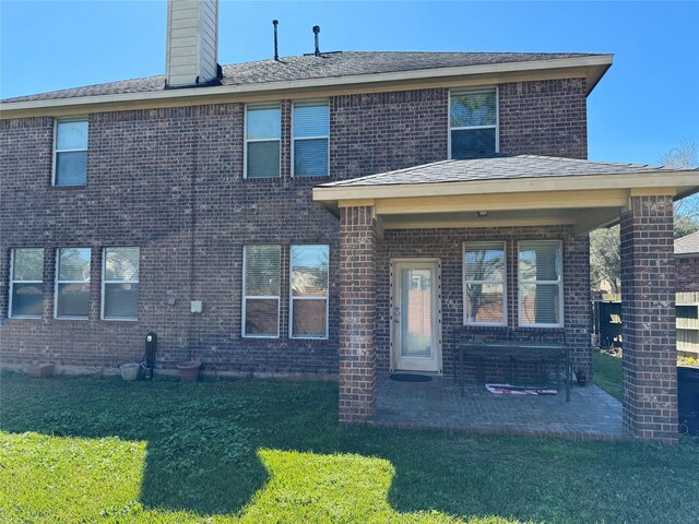 rear view of property with a yard, brick siding, and a chimney