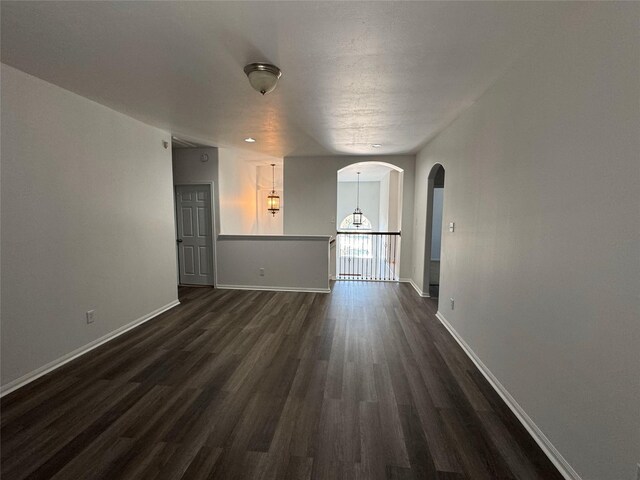 interior space with dark wood finished floors, arched walkways, and baseboards