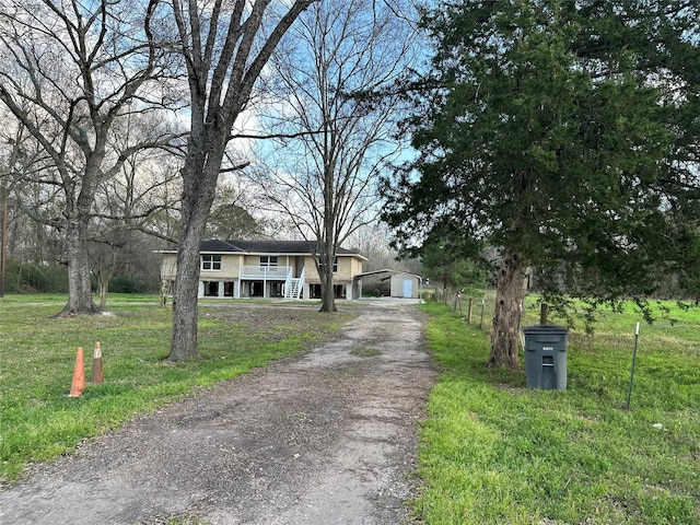 view of front of house featuring a garage, driveway, a front lawn, and an outbuilding