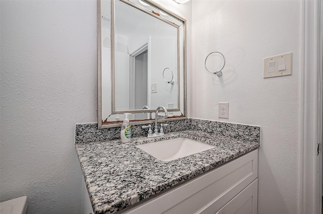 bathroom with a textured wall and vanity