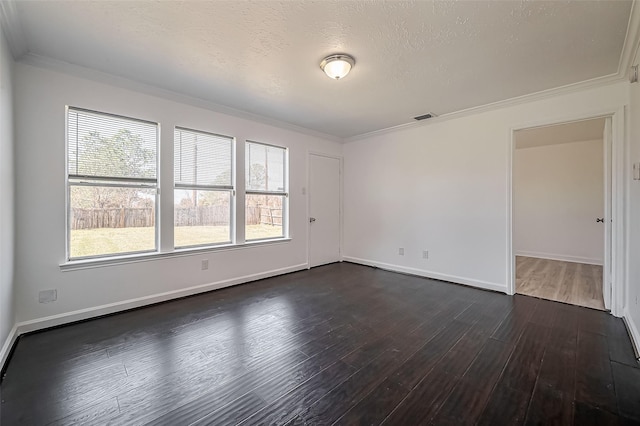 empty room featuring a healthy amount of sunlight, visible vents, ornamental molding, and dark wood-style flooring