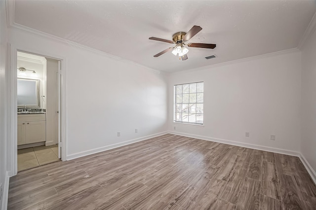 empty room featuring a sink, visible vents, crown molding, and wood finished floors