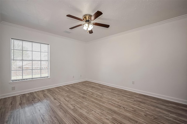 spare room with ornamental molding, visible vents, baseboards, and wood finished floors