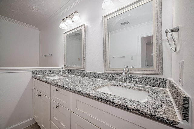 bathroom with double vanity, visible vents, ornamental molding, and a sink