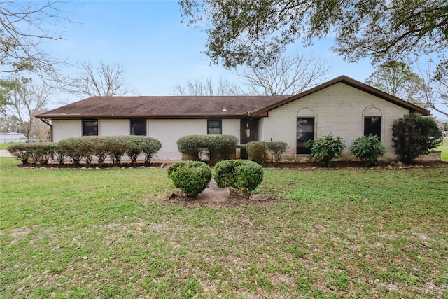 ranch-style home featuring roof with shingles, brick siding, and a front lawn