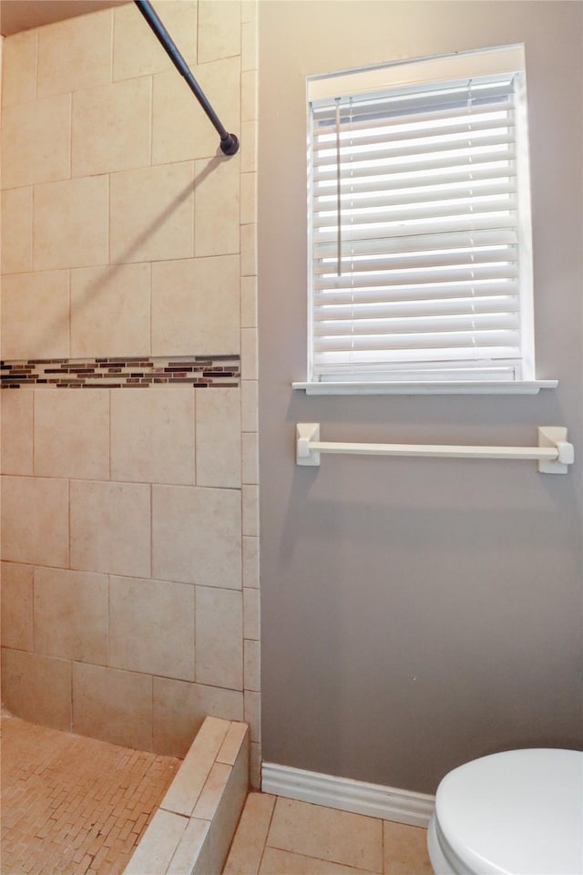 bathroom featuring toilet, a shower stall, baseboards, and tile patterned floors