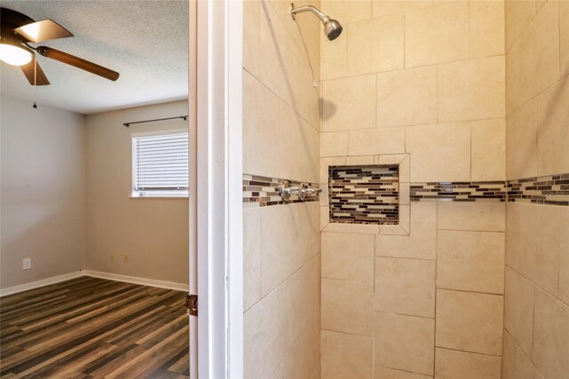 full bathroom with ceiling fan, a textured ceiling, wood finished floors, baseboards, and a tile shower