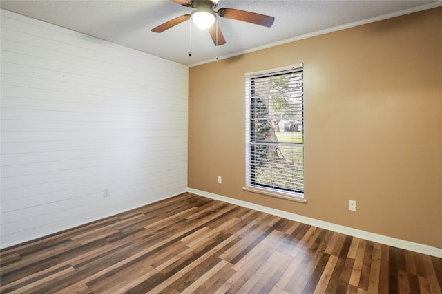 empty room featuring dark wood-style floors, crown molding, baseboards, and a ceiling fan