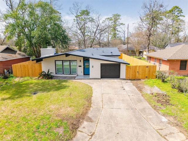 view of front of property featuring a chimney, concrete driveway, a front yard, fence, and a garage