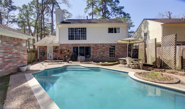 back of property featuring a patio area, brick siding, fence, and a chimney