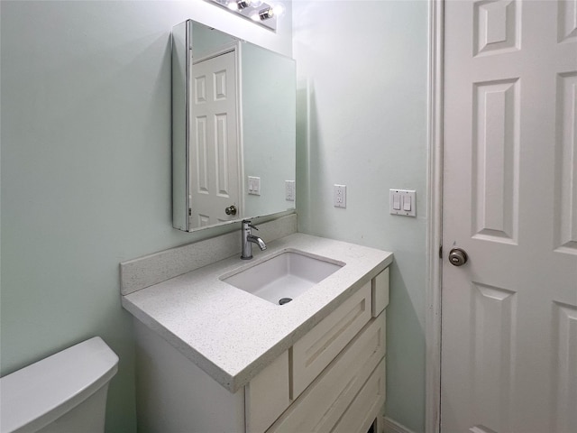 half bath featuring vanity and toilet