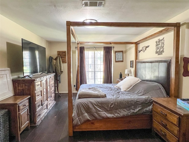 bedroom with a textured ceiling, dark wood-style flooring, and visible vents