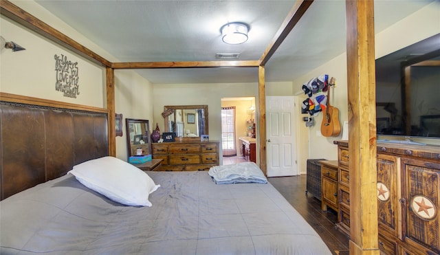 bedroom with connected bathroom, visible vents, and dark wood-style flooring