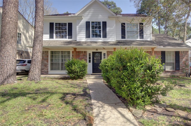 traditional-style home featuring roof with shingles and brick siding