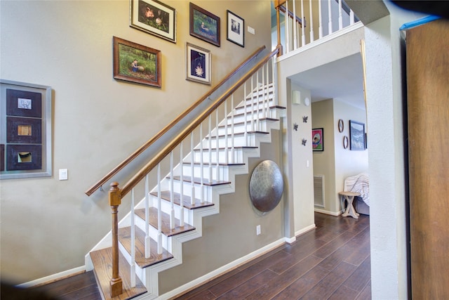 stairs with a high ceiling, baseboards, and wood finished floors