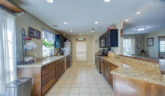 kitchen with light tile patterned floors, light stone countertops, stainless steel appliances, a sink, and recessed lighting