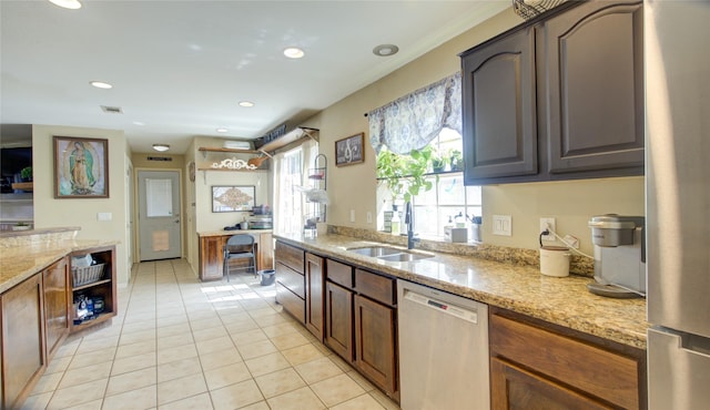 kitchen with light stone counters, recessed lighting, appliances with stainless steel finishes, light tile patterned flooring, and a sink