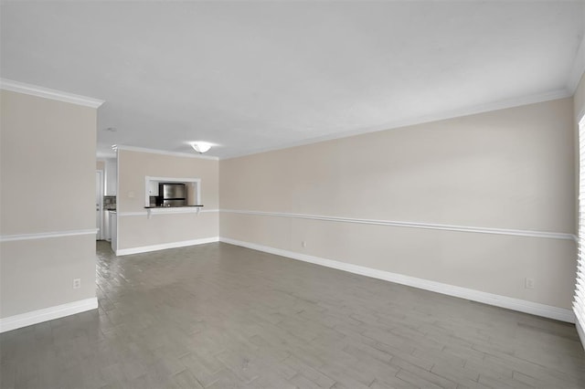 spare room featuring crown molding, dark wood finished floors, and baseboards