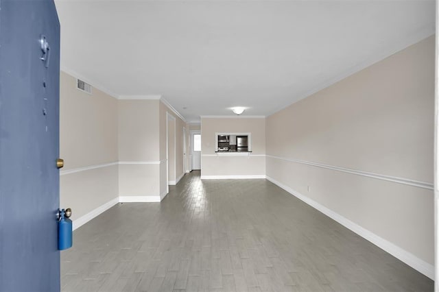 interior space featuring ornamental molding, wood finished floors, visible vents, and baseboards