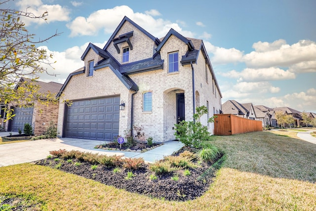 french country style house featuring concrete driveway, an attached garage, fence, and a front yard