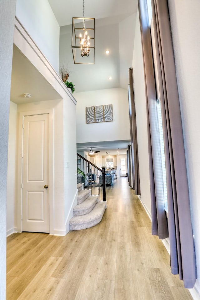 interior space featuring a chandelier, stairway, baseboards, and light wood-style floors