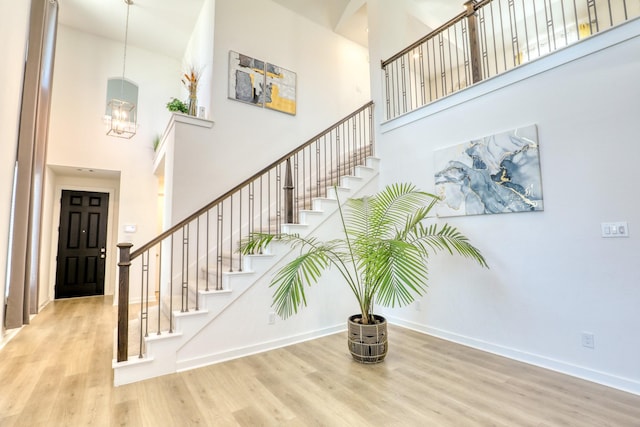 stairs featuring wood finished floors, a towering ceiling, and baseboards