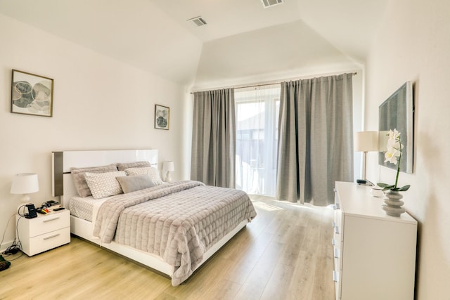 bedroom with light wood-type flooring, visible vents, and vaulted ceiling